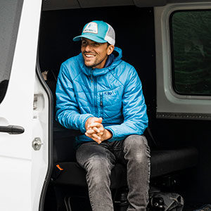 Photographer Justin Myers smiling while sitting on the step of a van