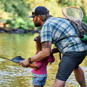 A man teaching a young girl to fly fish